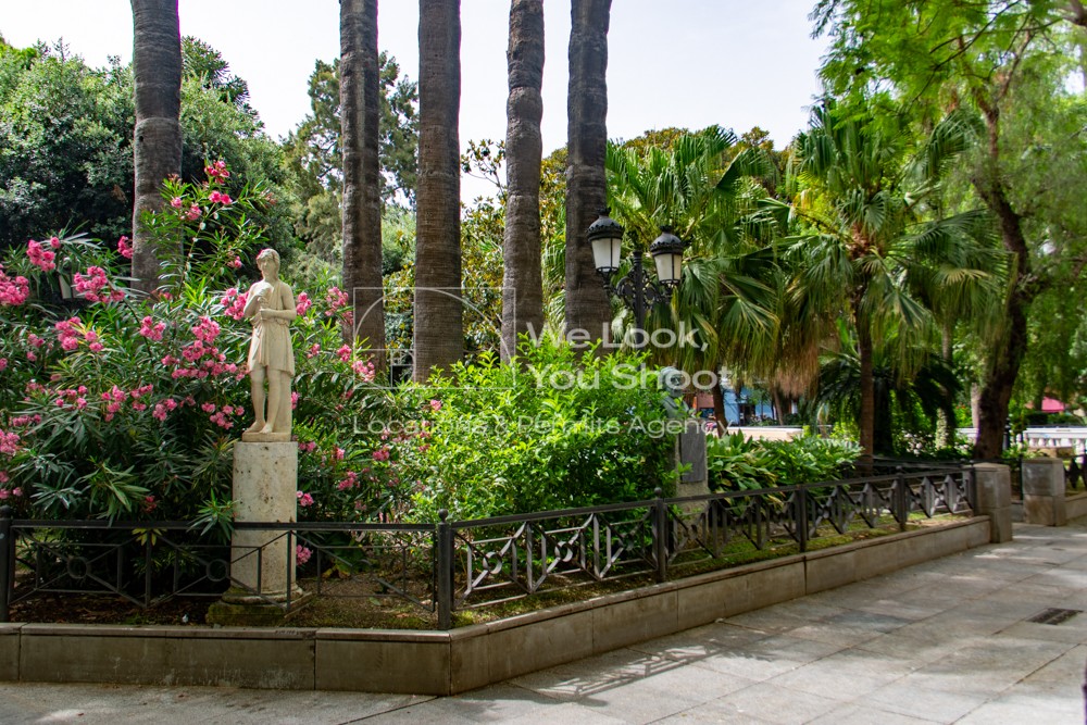 Jardines de la Plaza Mina con estatua, palmeras y farola