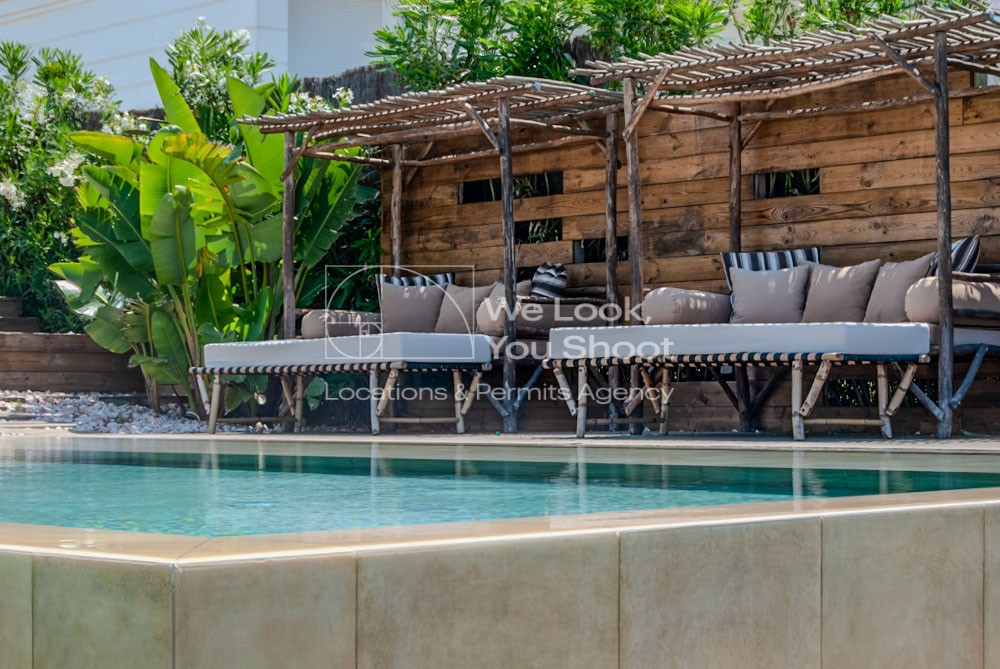 Camas balinesas en terraza de madera junto a piscina infinity pool