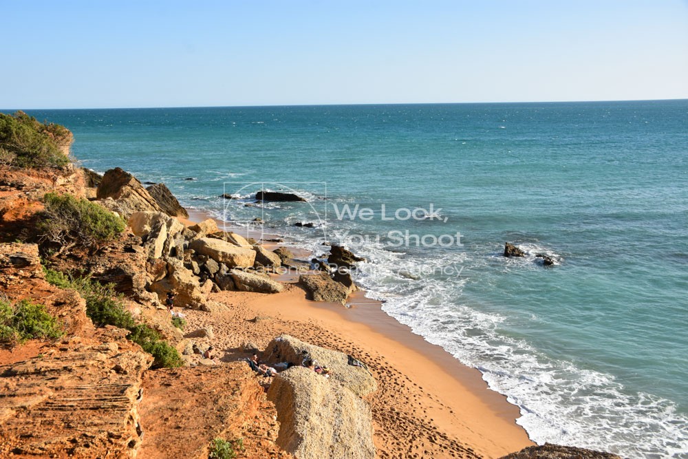 Playa de fina arena y aguas cristalinas con imponentes acantilados y rocas