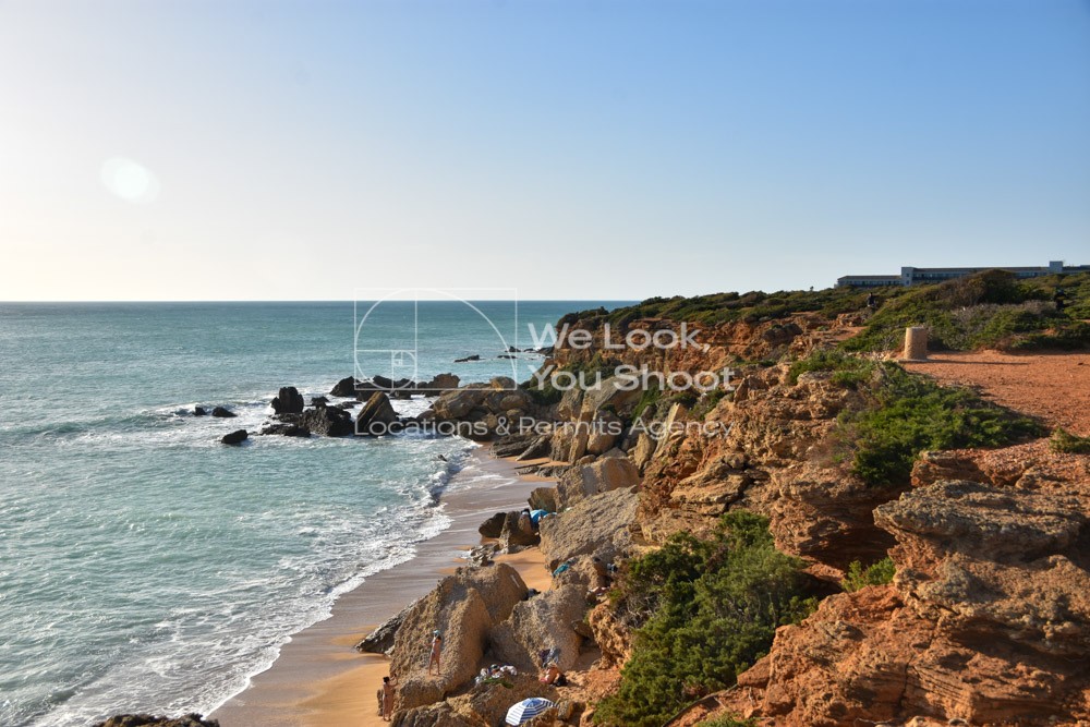 Playa de fina arena con imponentes acantilados y rocas