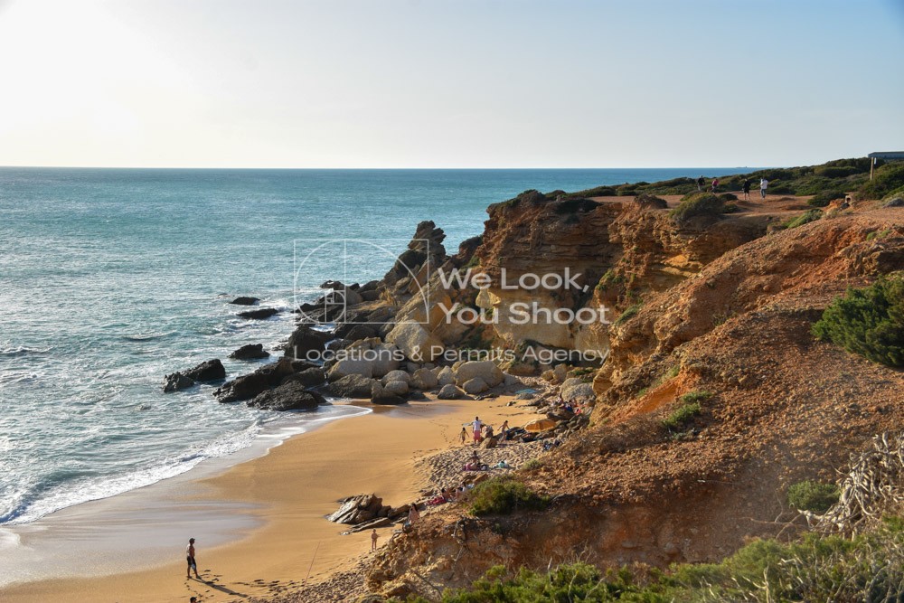 Pequeña cala de aguas tranquilas y arena dorada, rodeada de acantilados y vegetación