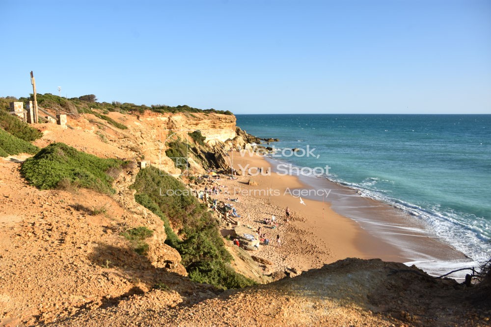 Pequeña cala de aguas tranquilas y arena dorada, rodeada de acantilados y vegetación